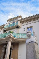 Un edificio clásico con balcones ornamentales y una estatua en primer plano.