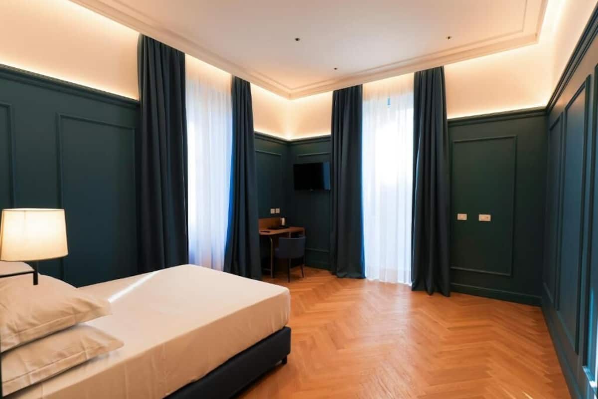 Une chambre d’hôtel avec un lit, un bureau, une chaise et un téléviseur.