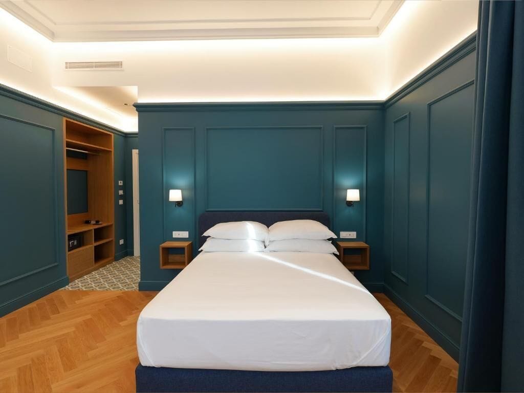 Ein Schlafzimmer mit einem großen Bett, zwei Nachttischen, einem Kleiderschrank und Wandleuchten.