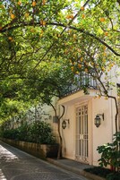 Un edificio de fachada blanca, entrada con portón y balcón con limones colgando.