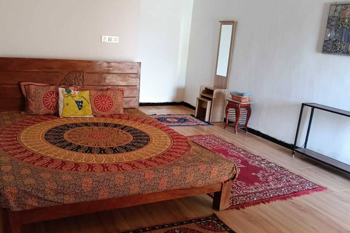 Un dormitorio con cama de madera, edredón estampado y alfombra roja.