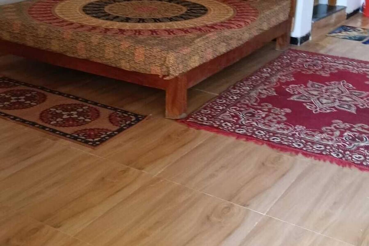 Un dormitorio con cama de madera, colcha estampada y dos alfombras.