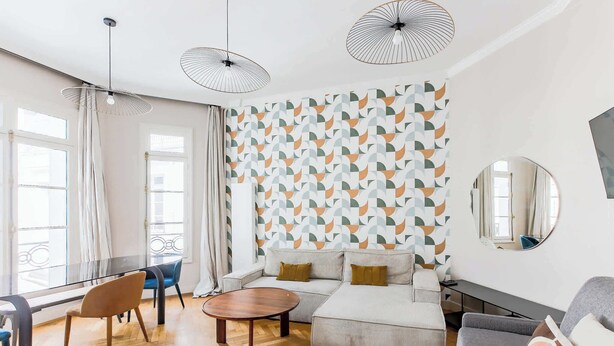 A modern living room with a sofa, coffee table, and chairs. There are two pendant lights and a large mirror on the wall. - Elegant apartment with suite - Arc de triomphe (Paris)