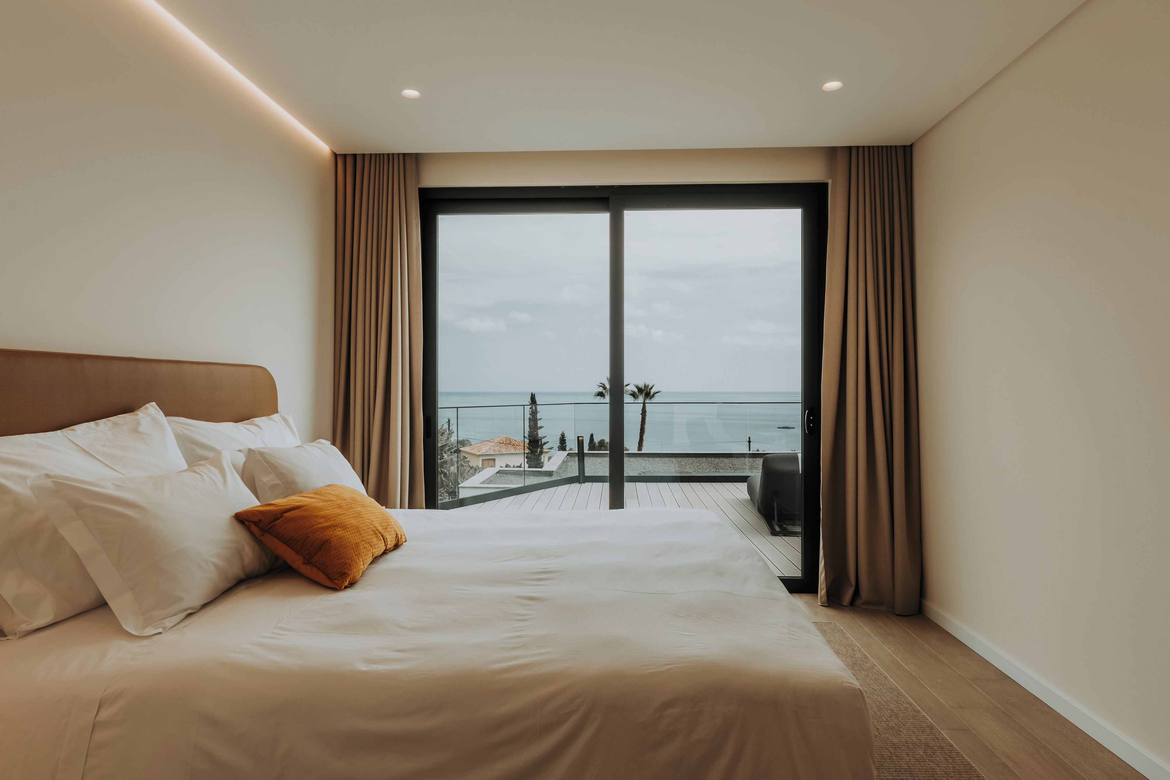 A hotel room with a large bed, a view of the sea, and a balcony.