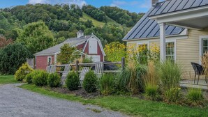 A rural property with a red barn, a white house with a porch, and a gravel driveway. - Little House at Saskadena, right at the base of Ski Hill (Pomfret)