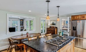 A kitchen with a large island, built-in shelves, a refrigerator, and pendant lighting.