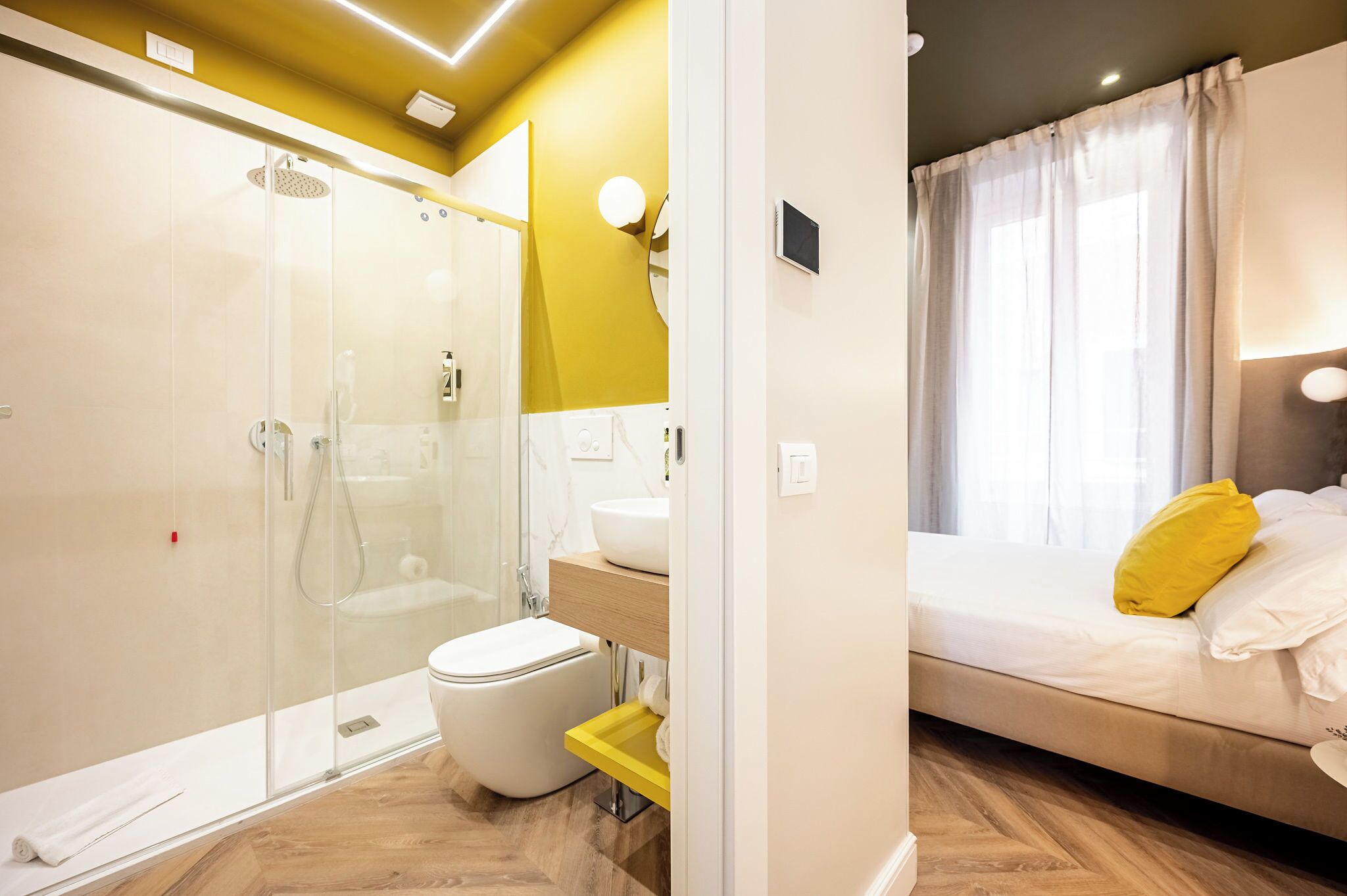 A modern bathroom with a glass shower enclosure, a toilet, and a sink with a mirror above.