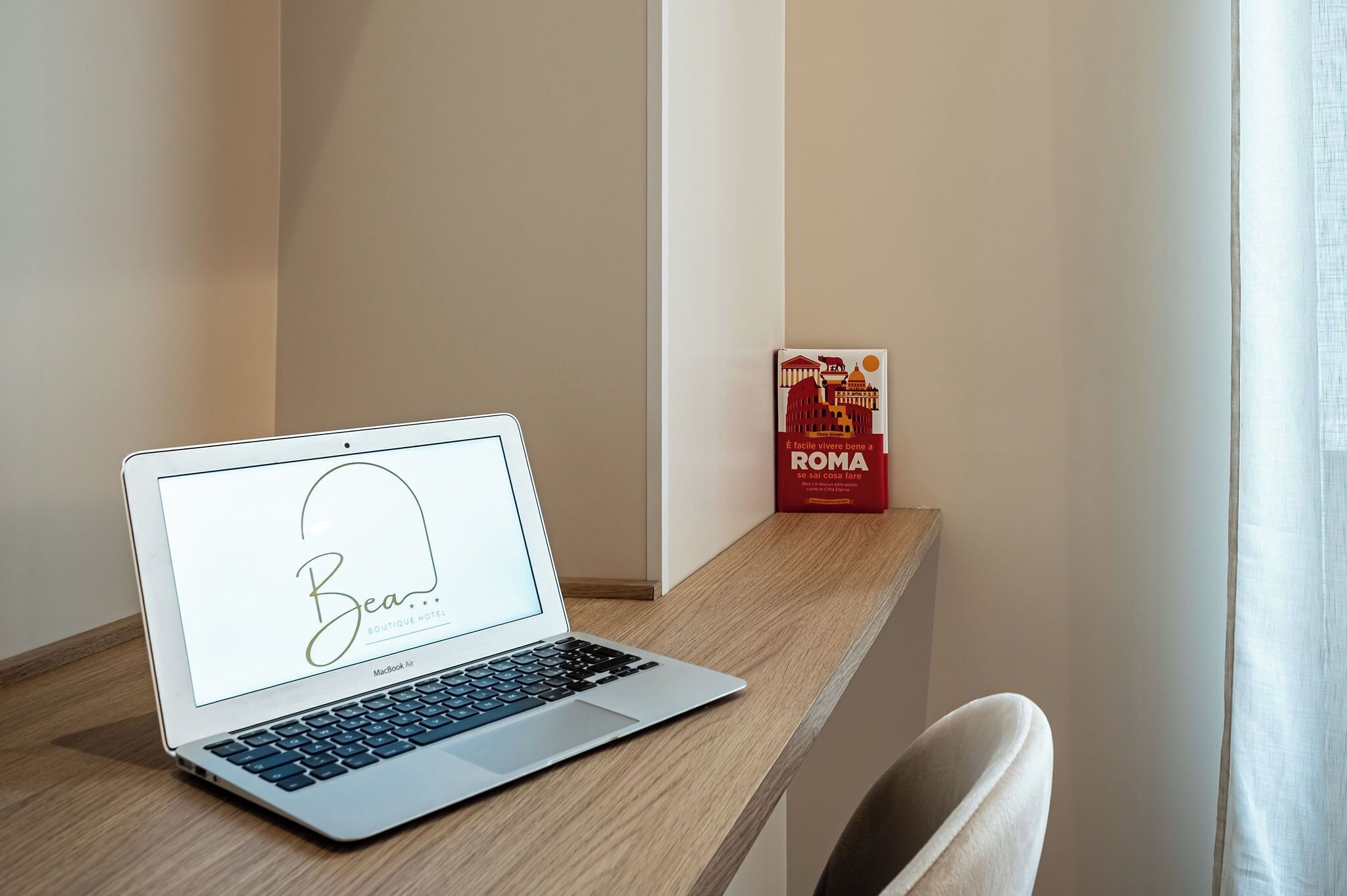 A laptop on a wooden desk with a red box labeled "ROMA" in the background.