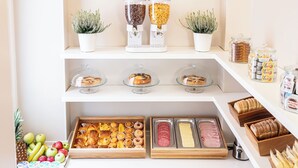 Un buffet de petit-déjeuner proposant une variété d’aliments et de pâtisseries présentés sur des étagères et dans des plateaux.