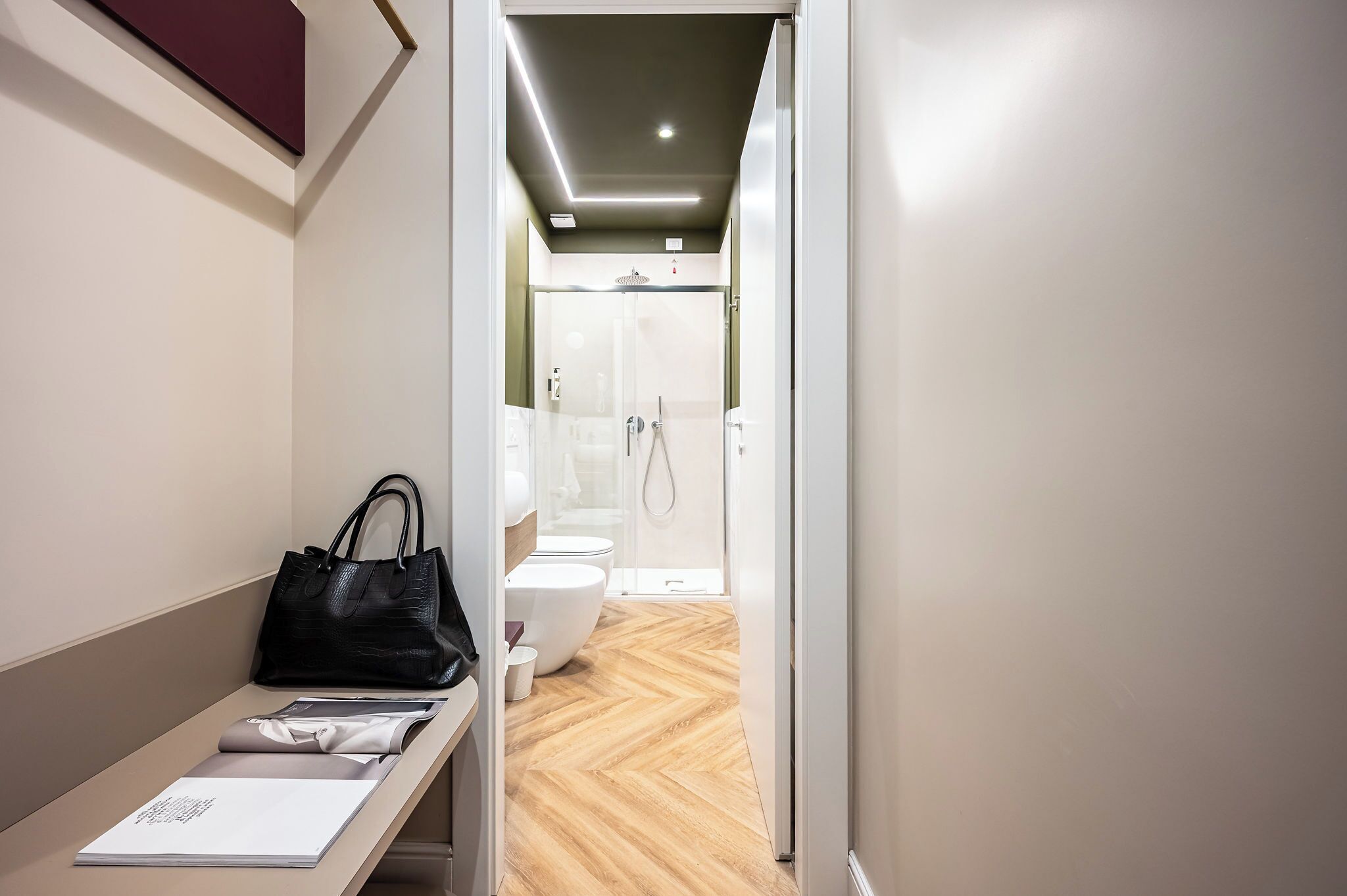 Ein modernes Badezimmer mit Dusche, Toilette und einem Schminktisch mit Handtasche und Papier.