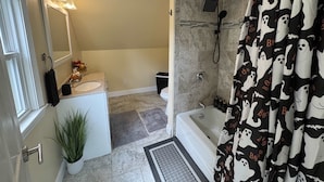 Een badkamer met een bad, douche en toilet.