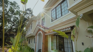 A two-story house with a balcony, surrounded by lush greenery. - Amã Stays & Trails Mudita Estates, Goa (Morjim)