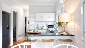 A modern kitchen with white cabinets, a black countertop, and three wooden stools.