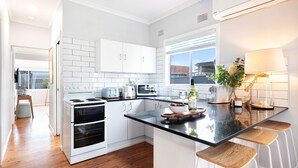 A modern kitchen with white cabinetry, a black countertop, and a large window providing natural light.