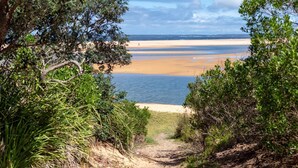 A coastal path leading to a beach with a clear view of the sea and distant shoreline.