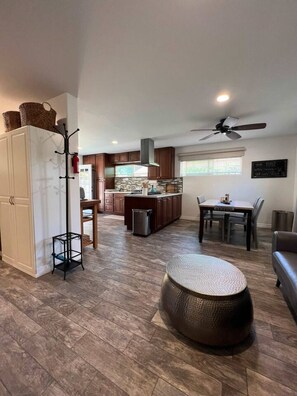 A modern kitchen with dark wooden cabinets, a central island, and a dining area with a table and chairs.