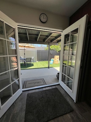 A covered patio with a sliding glass door leading to a backyard.