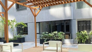 An outdoor patio area with wooden pergola, seating, and potted plants.