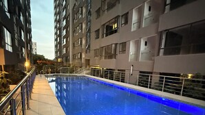 An indoor swimming pool with a tiled deck and metal railings.