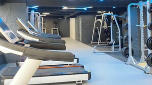 A gym with treadmills, weight machines, and a wall-mounted squat rack.
