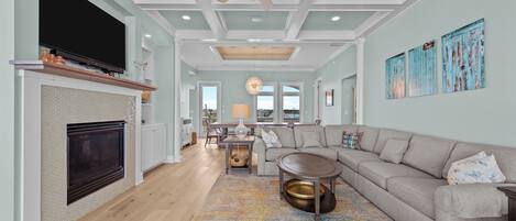 A spacious living room with a fireplace, a large sofa, and a ceiling fan.