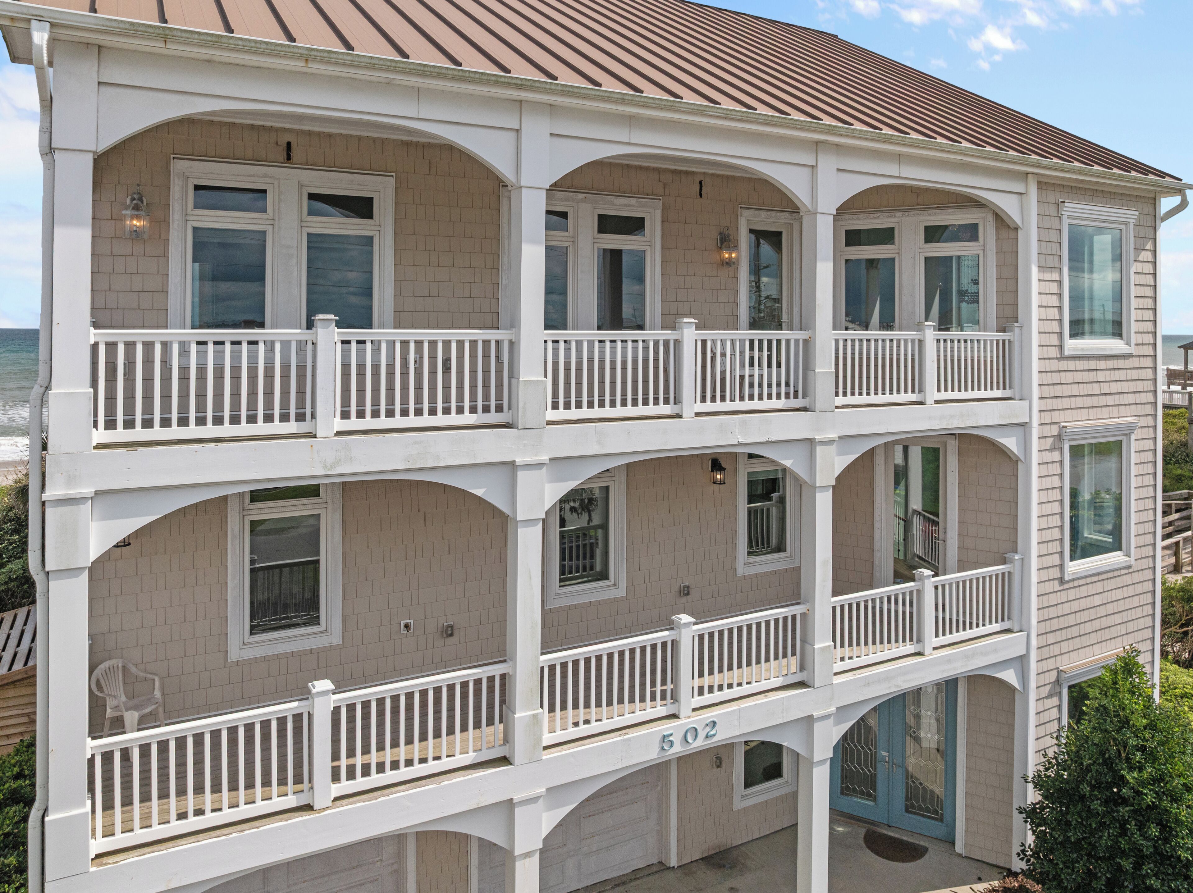 A multi-story building with a balcony on each floor, numbered 502, and a view of the ocean.