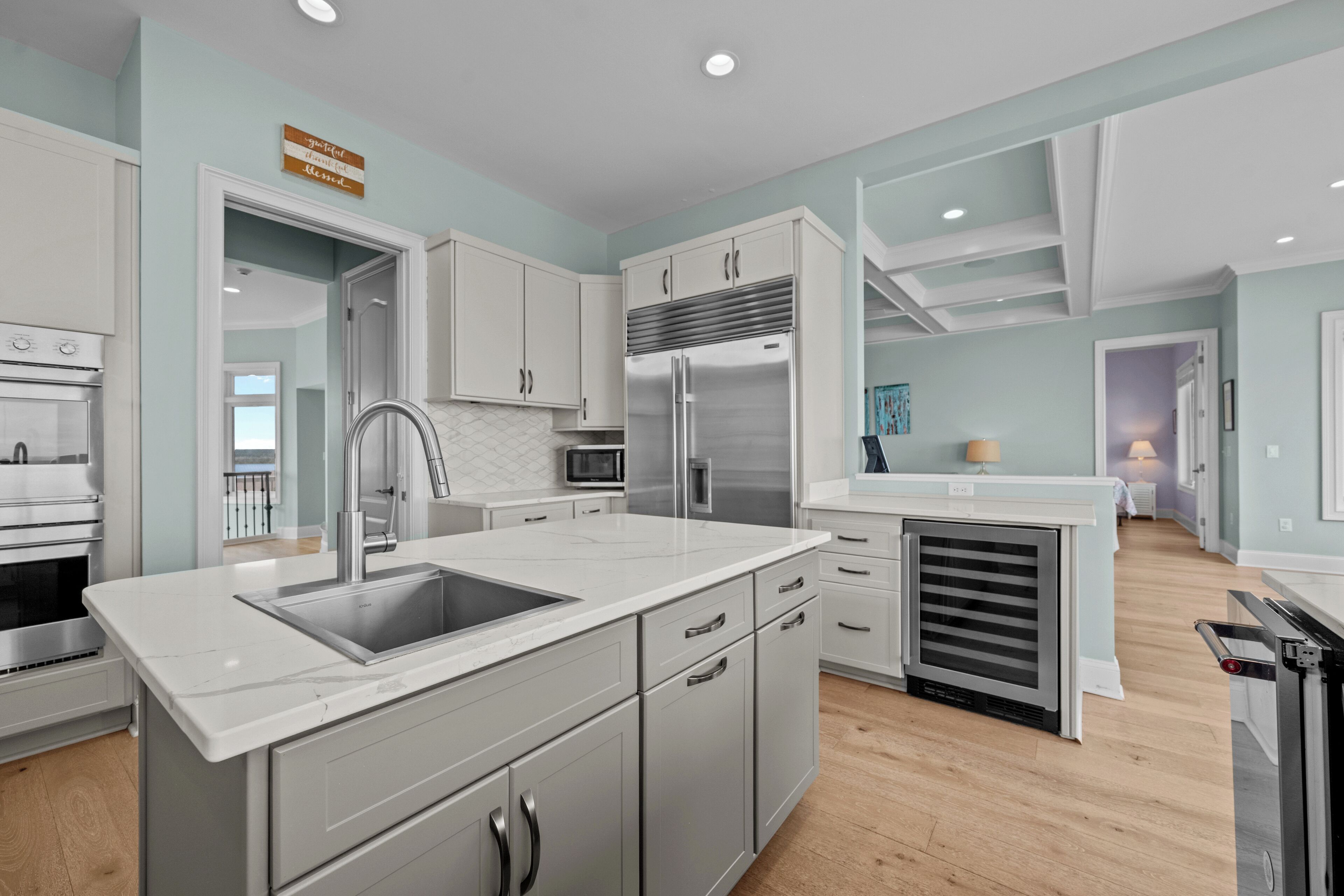 A modern kitchen with stainless steel appliances, white cabinetry, and a marble countertop.