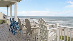 A wooden deck with Adirondack chairs overlooking a beach. - North Shore Paradise #199 - 7 BR, 7.5 BA Oceanfront Home w/ Pool & Hot Tub (Surf City)