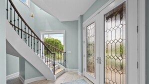 A staircase with a white railing and a blue rug leading to a door with a glass panel. - North Shore Paradise #199 - 7 BR, 7.5 BA Oceanfront Home w/ Pool & Hot Tub (Surf City)