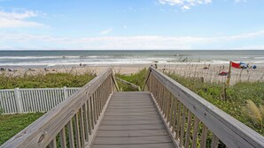 A wooden boardwalk leading to a beach with a clear view of the ocean and beachgoers. - North Shore Paradise #199 - 7 BR, 7.5 BA Oceanfront Home w/ Pool & Hot Tub (Surf City)