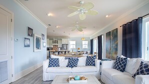 A spacious living room with a white sofa, a coffee table with decorative items, and a ceiling fan. - Secluded Dunes gulf view with elevator, private pool, VayK Gear (Port St Joe)