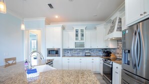 A modern kitchen with granite countertops, stainless steel appliances, and white cabinetry. - Secluded Dunes gulf view with elevator, private pool, VayK Gear (Port St Joe)