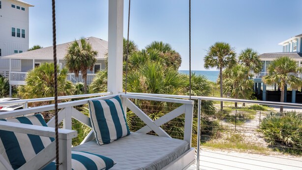 A white outdoor seating area with striped cushions, overlooking a beach with palm trees and a clear blue sky. - Secluded Dunes gulf view with elevator, private pool, VayK Gear (Port St Joe)