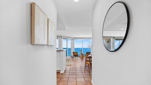 A hallway with a tiled floor, a wooden door, and a view of a balcony with a table and chairs. - Top of the Wave - Oceanfront top floor breathtaking views with AC (Solana Beach)