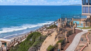 A coastal hotel with a beach view, a pool area, and a staircase leading down to the beach. - Top of the Wave - Oceanfront top floor breathtaking views with AC (Solana Beach)