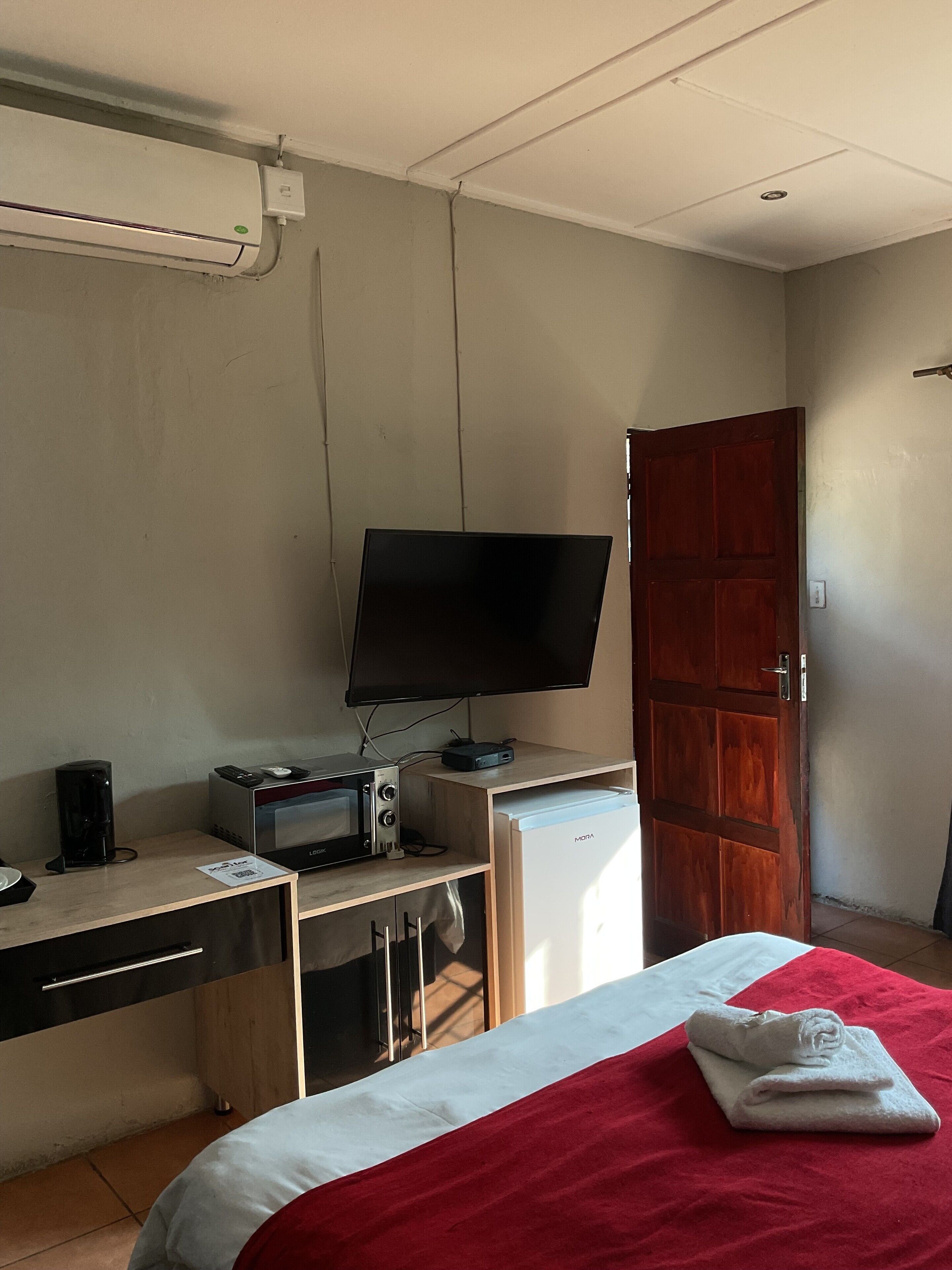 Una habitación de hotel con una cama, un escritorio con televisor, microondas y cafetera.