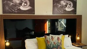 A hotel room with a large bed, two nightstands, a red throw blanket, and two wall-mounted artworks. - Bothabelo Lodge (Phalaborwa)