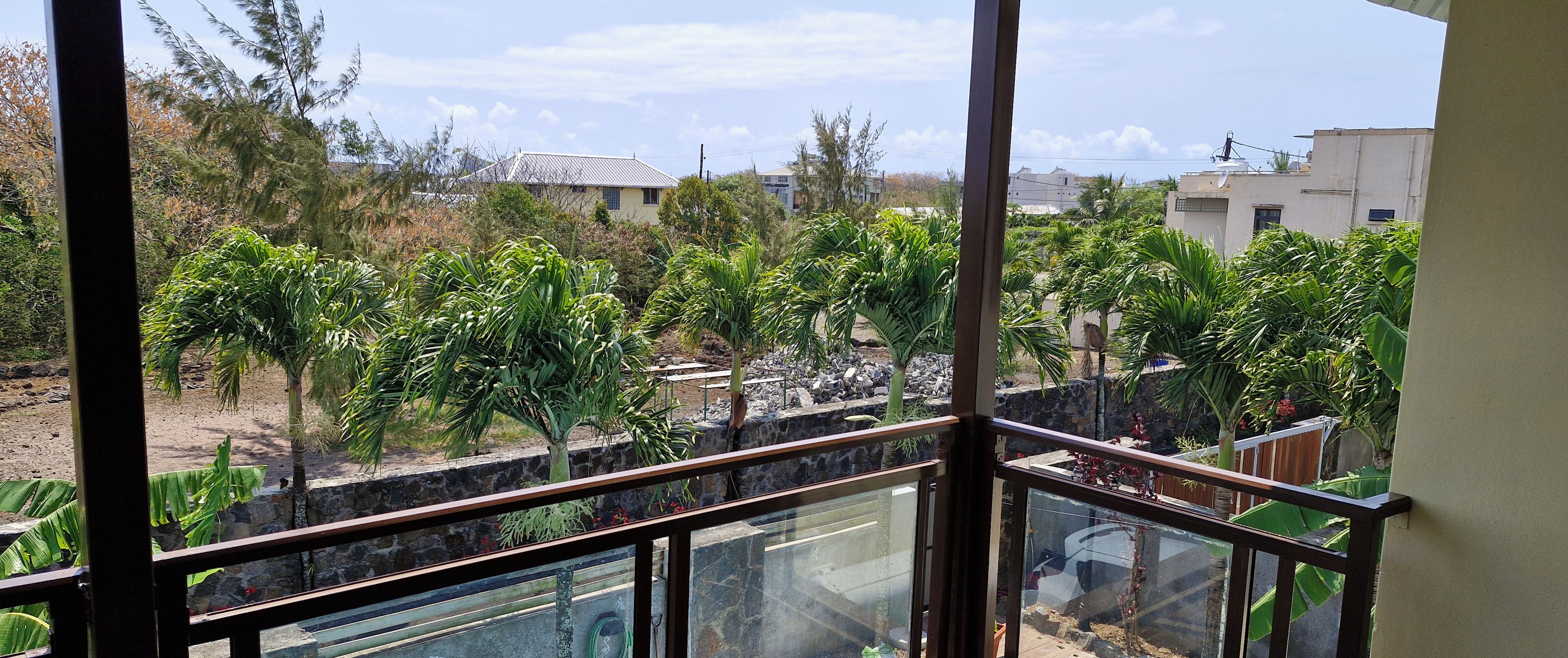 A balcony with a view of a garden and buildings.