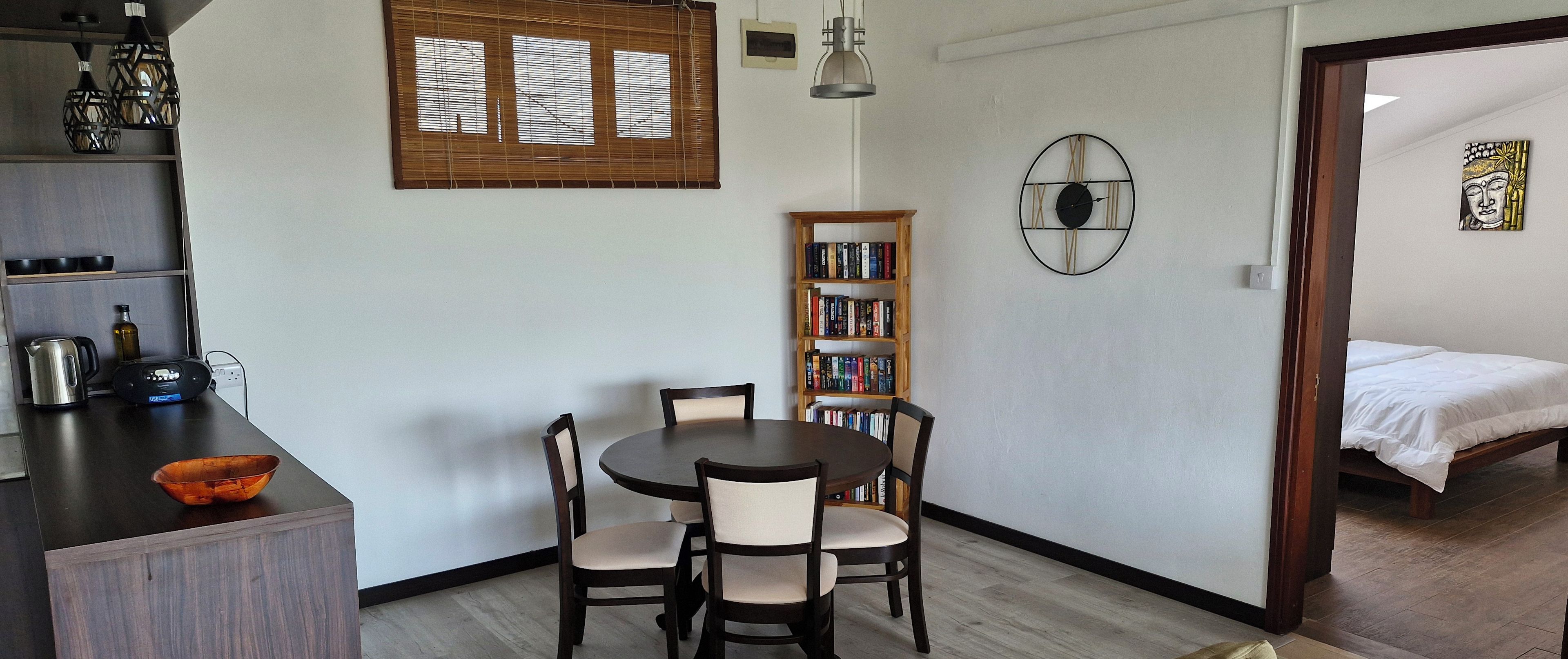 Un espace de vie compact comprenant un coin repas, une bibliothèque et un lit.