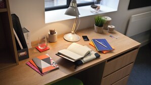 A neatly organized desk with a lamp, books, a notebook, and a smartphone. - Student Only Algernon Firth (Leeds)