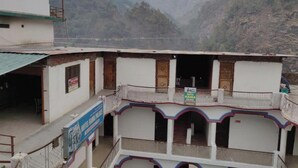 A hotel with multiple balconies, a signboard for Hotel Rama Palace, and a view of a mountainous landscape. - Hotel Rama Palace (Ukhimath)