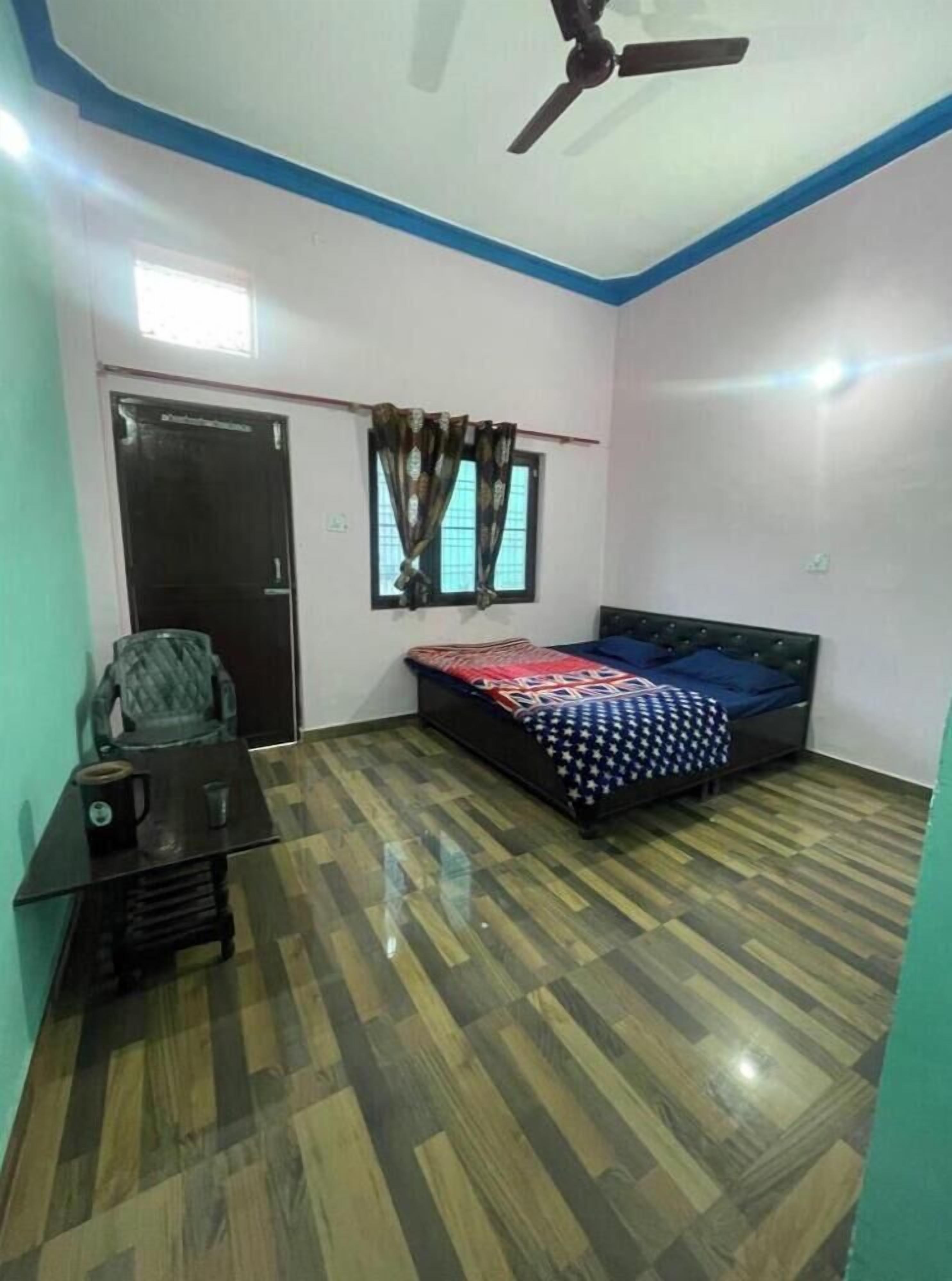 Una camera da letto con un letto, una scrivania, una sedia, una ventola a soffitto e una finestra con tende.