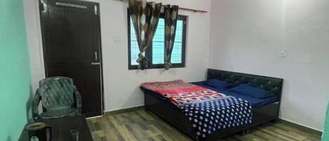 Una camera da letto con un letto, una scrivania, una sedia, una ventola a soffitto e una finestra con tende.