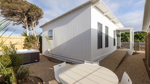 A modern house with a covered patio, a hot tub, and a small garden area.
