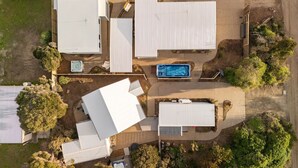 Vista aérea de una zona residencial con varias casas unifamiliares, piscina y abundante vegetación.