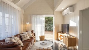Una sala de estar moderna con un sofá de cuero, una mesa de centro y un televisor sobre un soporte de madera.