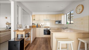 Una cocina moderna con armarios de madera, horno empotrado, microondas y un ventanal grande.