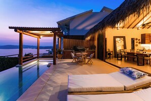 A modern outdoor lounge area with a pool, seating, and a dining setup.