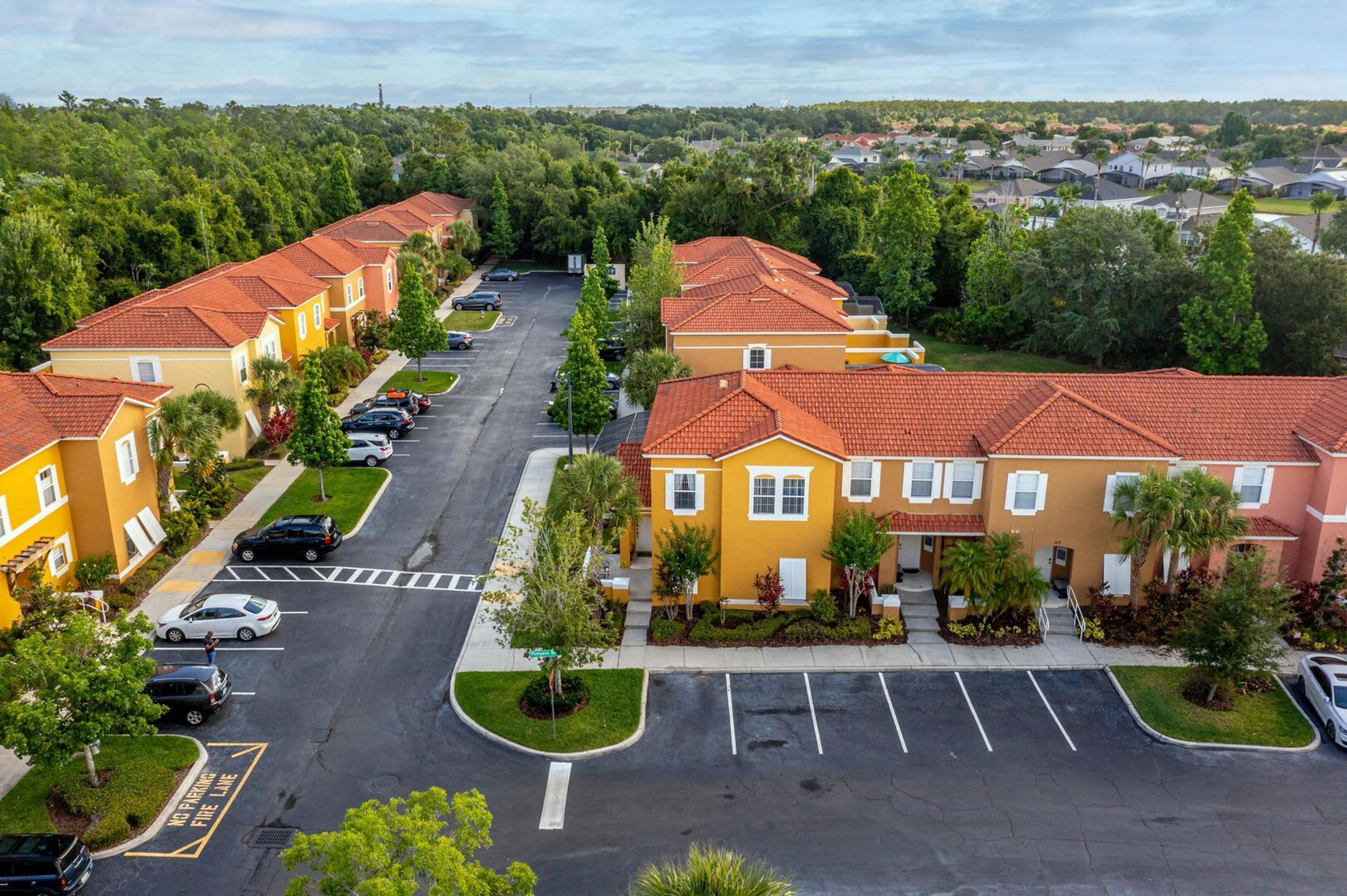 A residential area with yellow buildings, red roofs, and a parking lot.