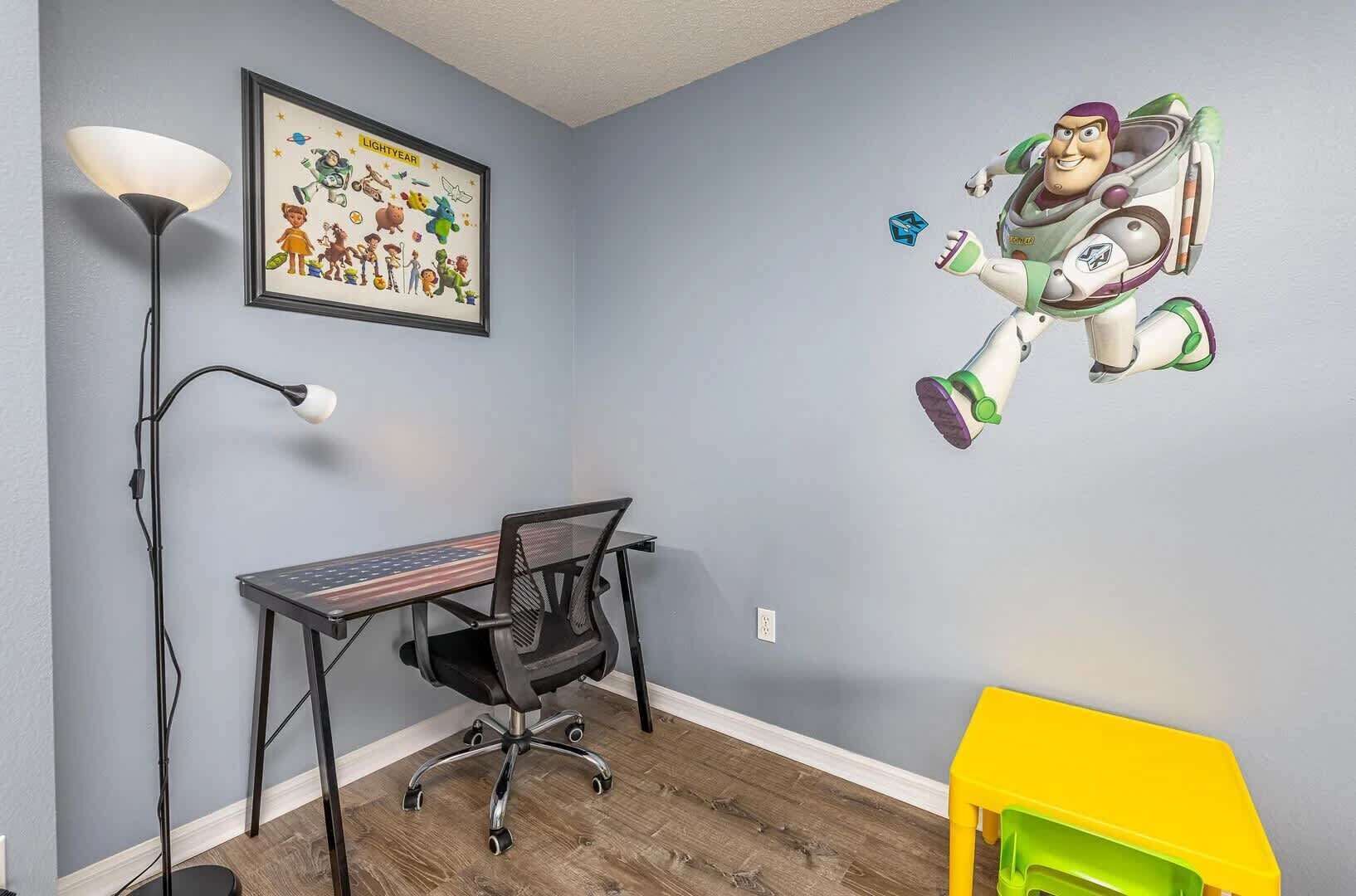 A room with a desk, chair, and a wall decal of a character.